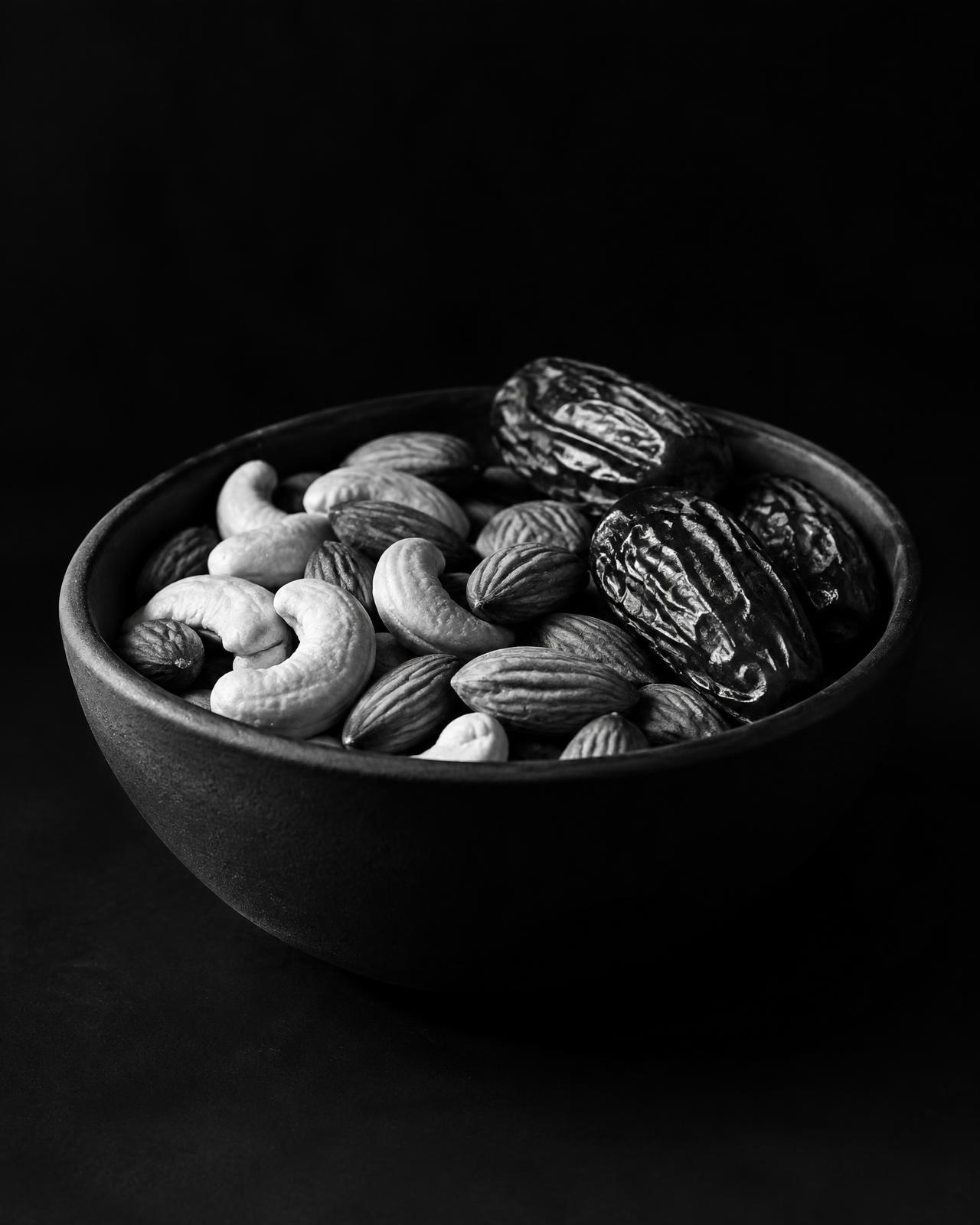 Cashews, almonds and dates in a dark bowl